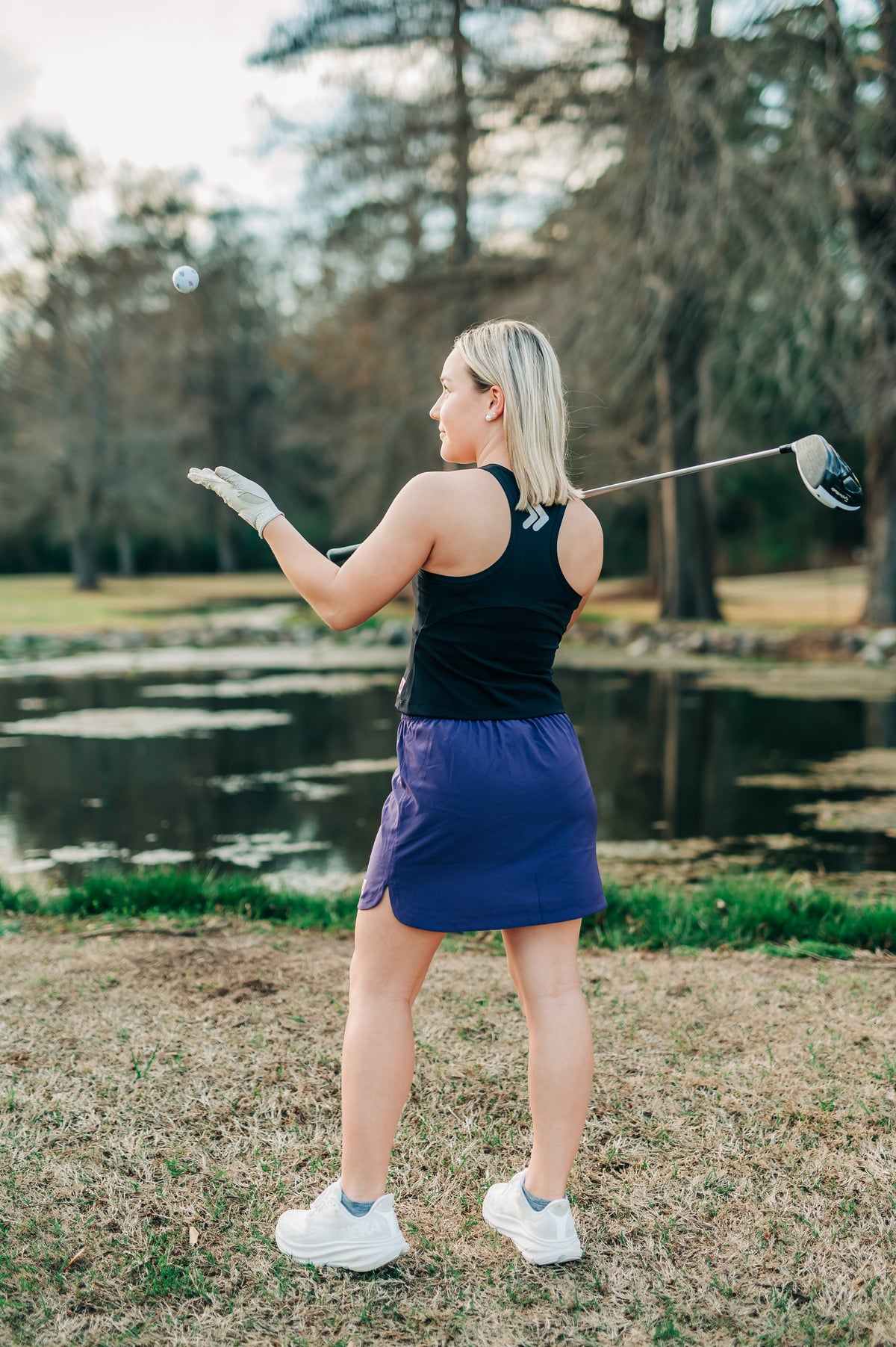 Woman wearing a purple MOVE Sport Apparel women’s Skort with a black sleeveless top on a golf course.