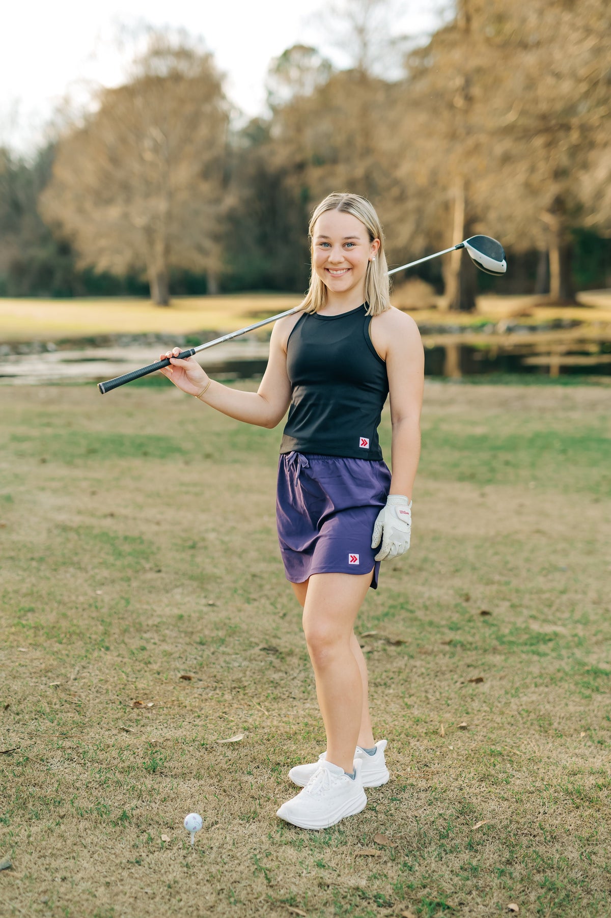 Woman wearing a purple MOVE Sport Apparel women’s Skort on an outdoor golf course.