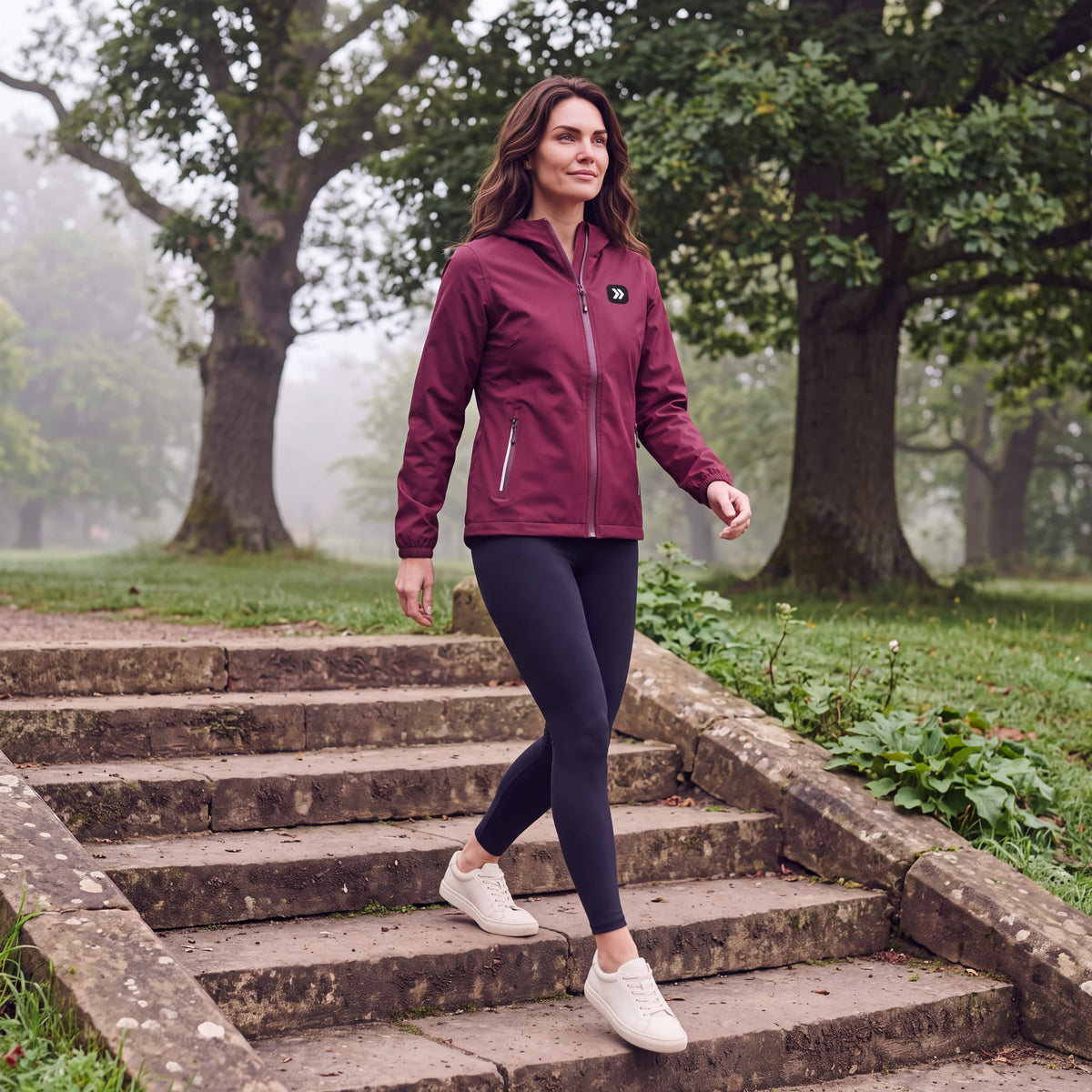 Woman walking on stone park steps in the Windsor Wine MOVE Sport Apparel women’s Soft Shell Jacket, black leggings and off-white trainers.