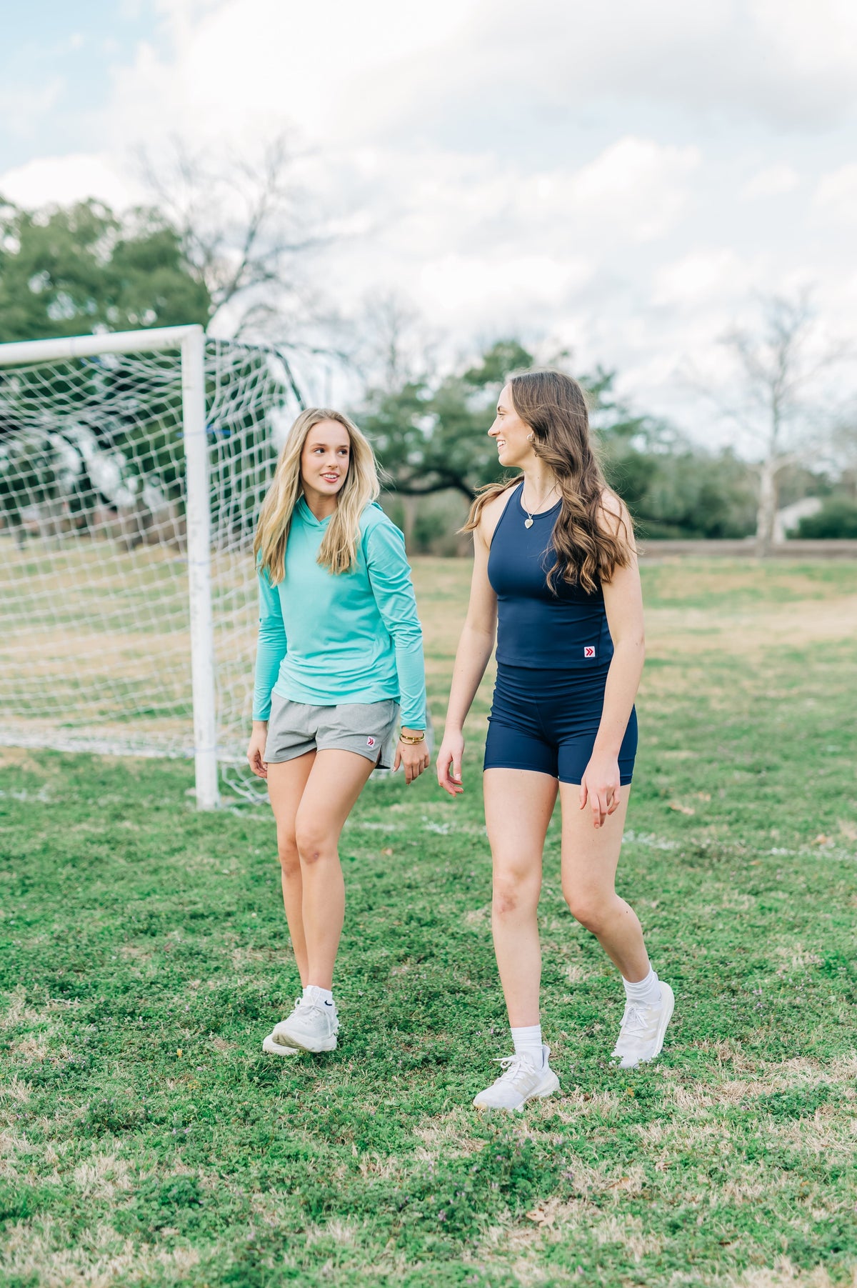MOVE Sport Apparel women’s Black Label Lightweight Sun Hoodie: Woman wearing Aqua Splash sun hoodie beside a friend on a grass field.
