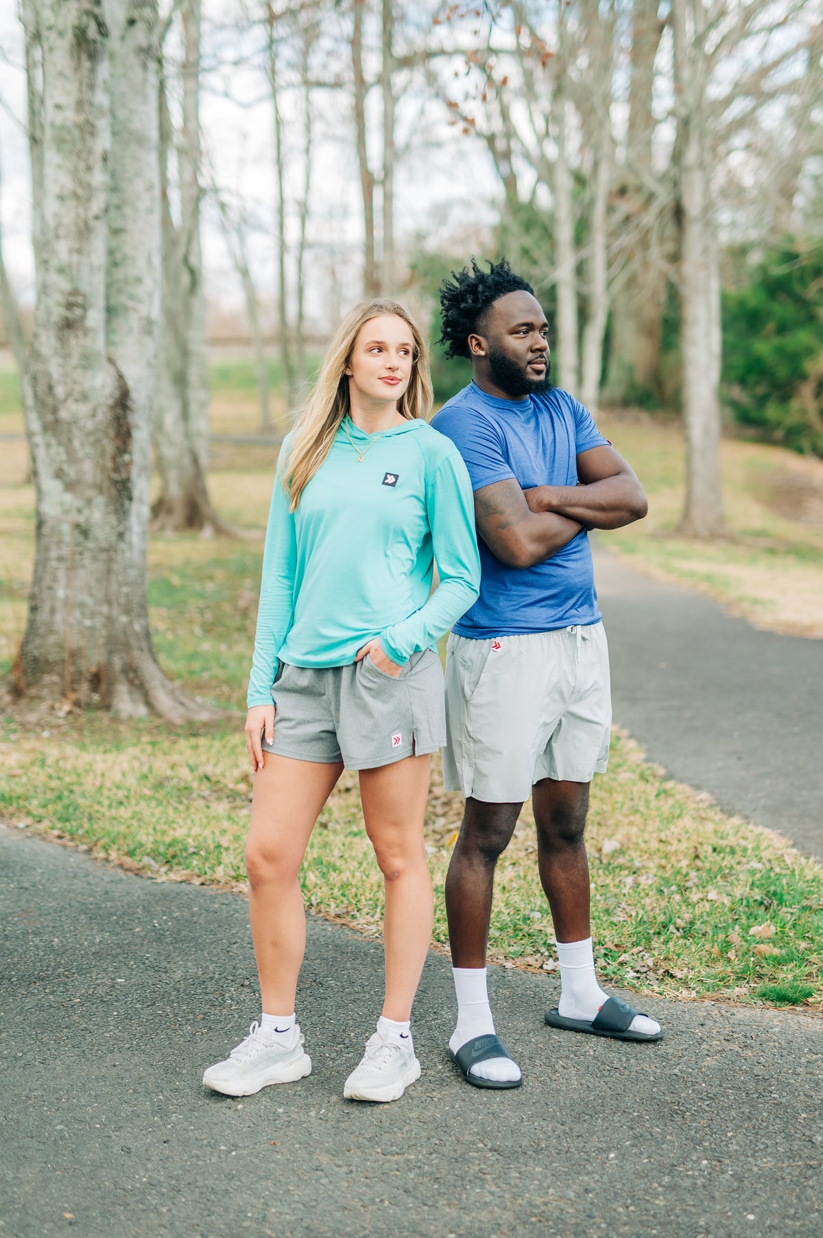 MOVE Sport Apparel women’s Black Label Lightweight Sun Hoodie: Front view of a woman wearing Aqua Splash sun hoodie beside a man on a wooded path.