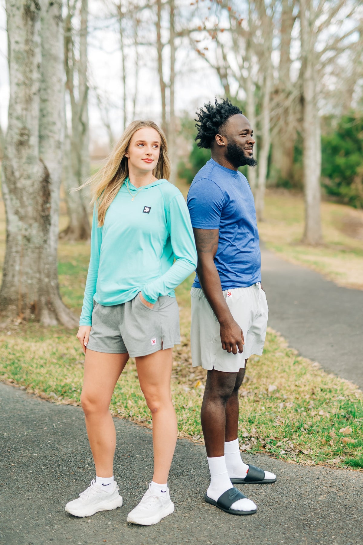 MOVE Sport Apparel women’s Black Label Lightweight Sun Hoodie: Woman wearing Aqua Splash sun hoodie beside a man on a wooded path, side view.