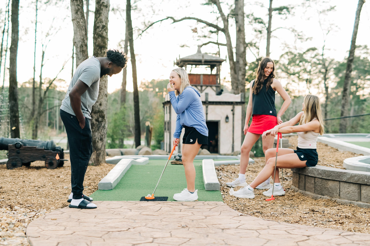 MOVE Sport Apparel women’s Black Label Lightweight Sun Hoodie: Friends playing miniature golf with a woman wearing the Deep Periwinkle sun hoodie.